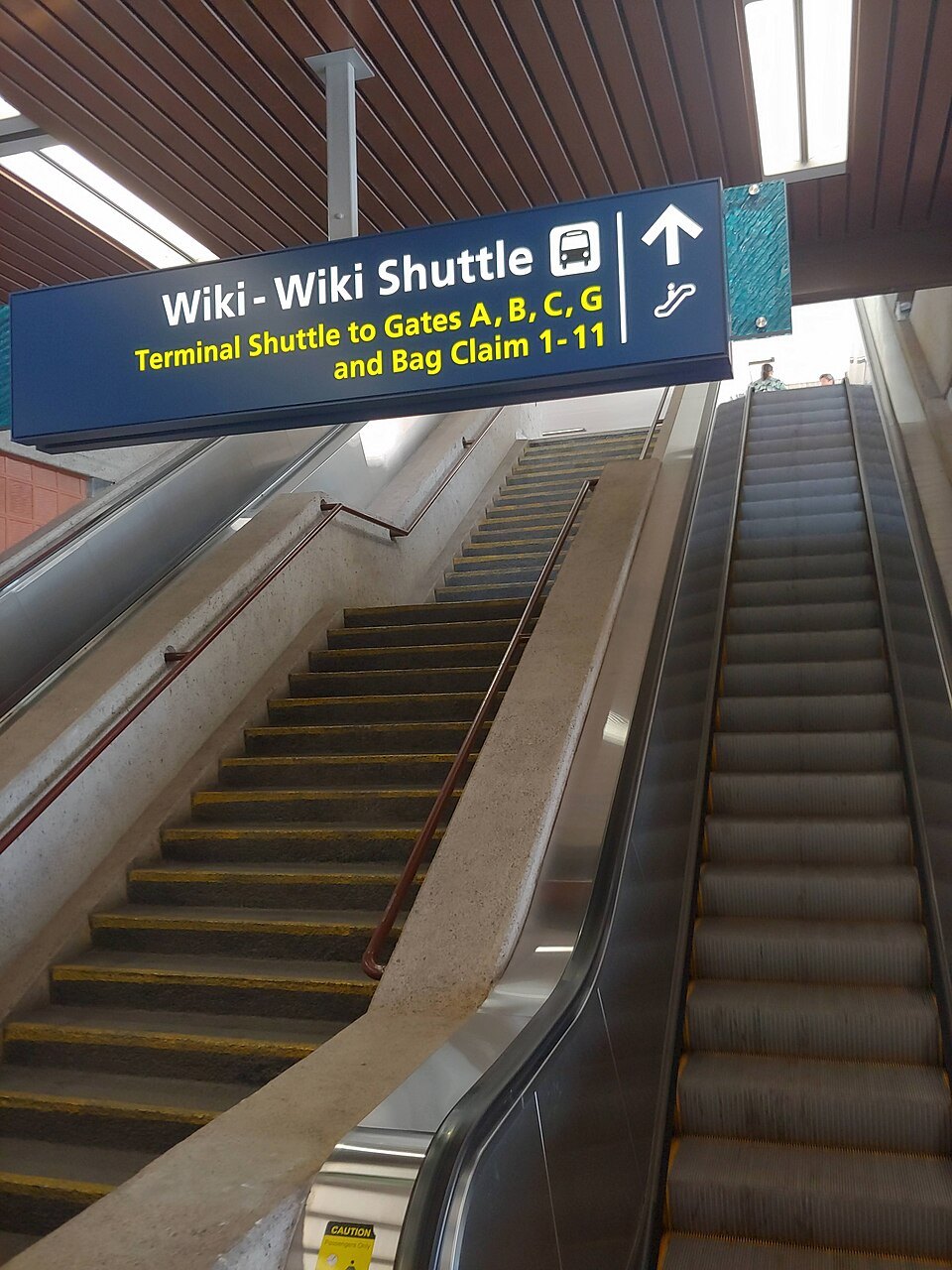 The escalators down to the Wiki Wiki Shuttle, with signs to the gates