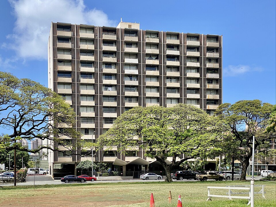 An apartment block behind monkeypod trees on Beretania Street