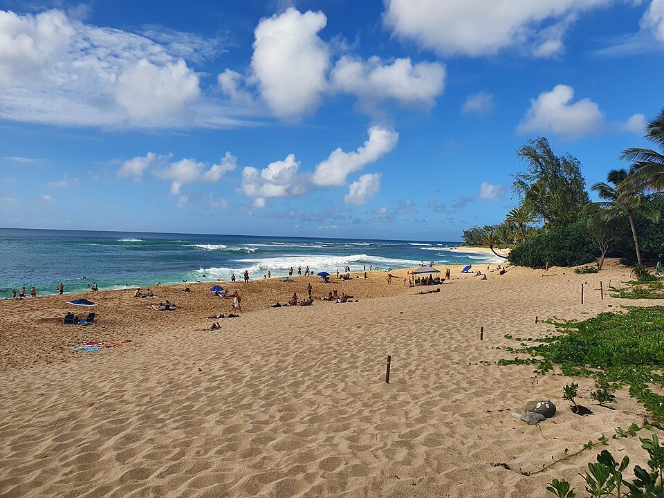 The wide sand of the North Shore, with the winter surf breaking