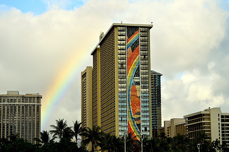 A rainbow beside the mosaic tower of a Waikīkī hotel