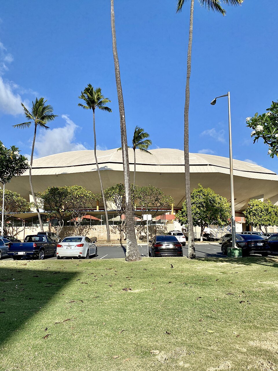 The folded roof of the Blaisdell Arena behind its lawn