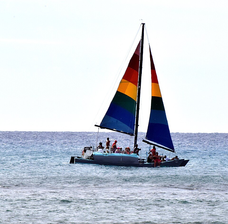 A catamaran with rainbow sails off Waikīkī