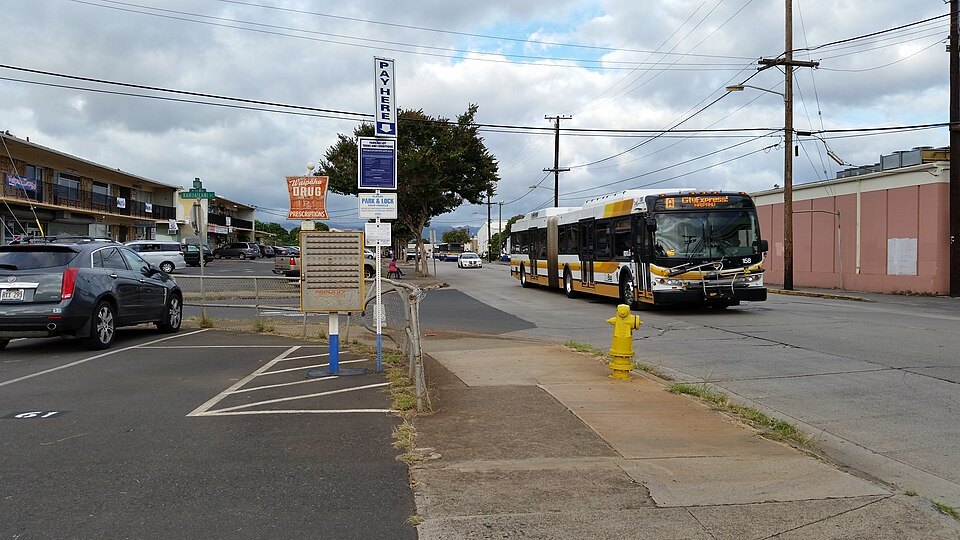A TheBus articulated coach pulling in along a wide avenue