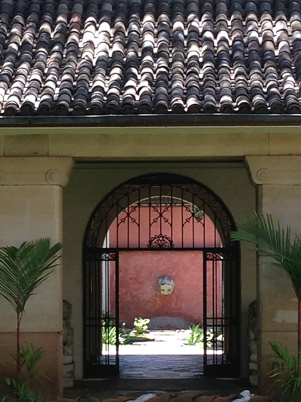 An arched gate into a museum courtyard, framed by tile roofs