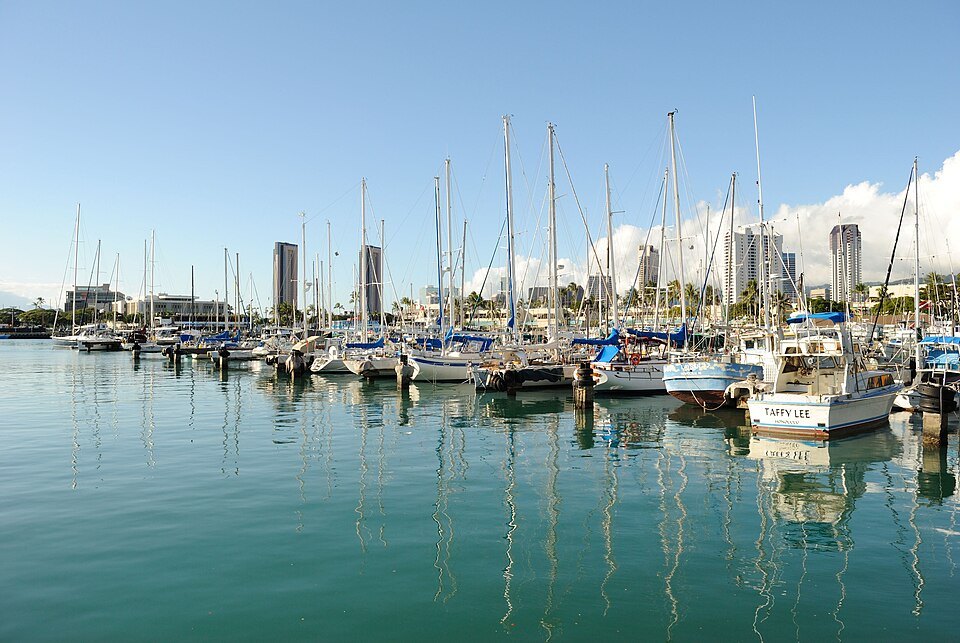 Sailboats lined up at Kewalo Basin, the Kakaʻako towers beyond
