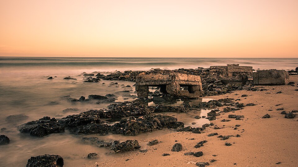 Rocks and an old seawall at low tide in the afterglow