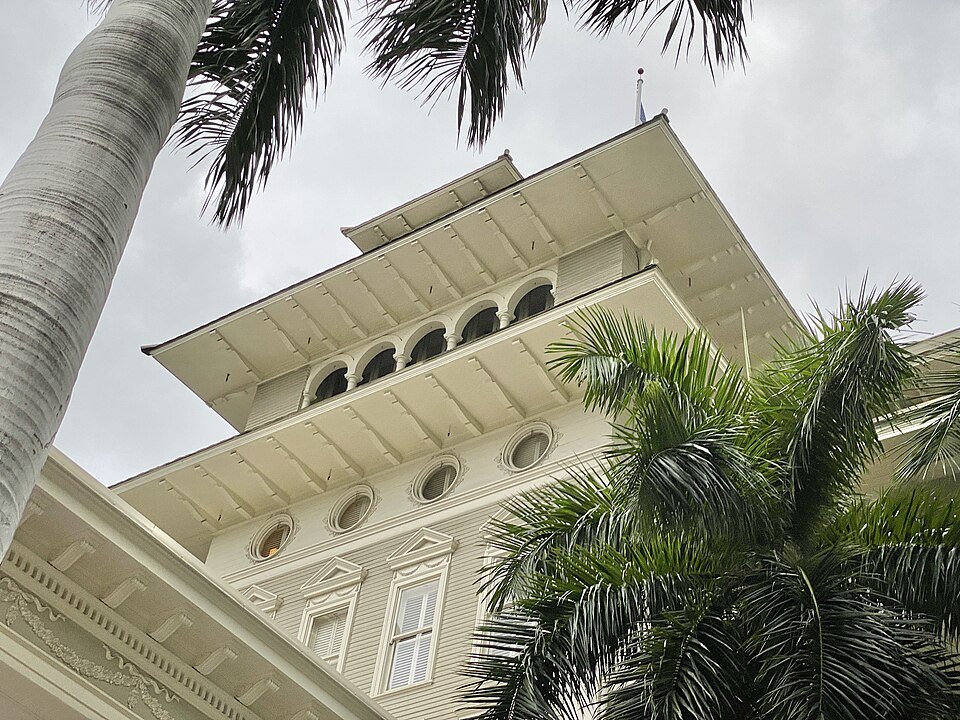 The Moana Hotel's tiered crown, seen from below the palms